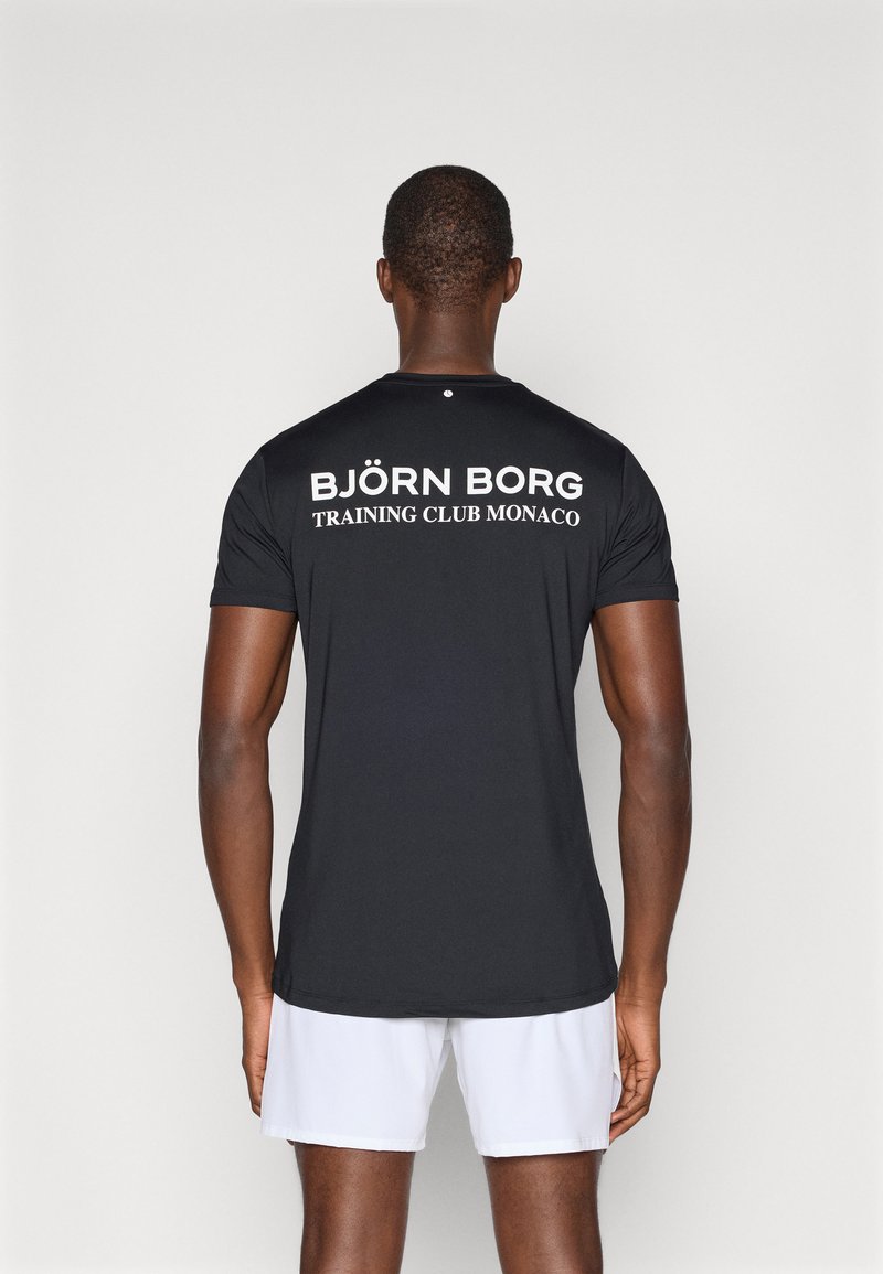 Juodas trumpas rankovės sportinis marškinėliai su bold baltu užrašu "BJÖRN BORG TRAINING CLUB MONACO" nugaroje, lygus audinys ir standartinė apykaklė.