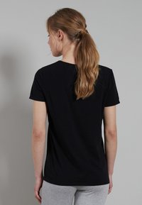 Black short-sleeve t-shirt in soft material, with a round neckline and a slim fit. Back view shows smooth texture and no visible logos.