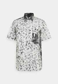 Camicia a maniche corte con bottoni in bianco e nero; presenta un motivo a macchie, tasca con stampa snake in contrasto e inserti in hardware nero.
