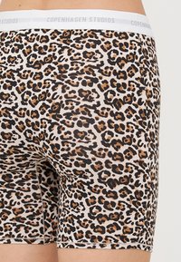 Løveprint boxershorts i beige med sorte og brune pletter, med en hvid elastisk talje med "Copenhagen Studios" branding.