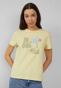 Geel katoenen t-shirt met een speelse grafische print met "Aloha" in het groen, een blauwe palmboom en een rode cirkel. Korte mouwen, ronde halslijn.