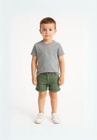T-shirt gris à manches courtes, shorts verts retroussés, et baskets blanches à enfiler. Design simple, matériau en coton, coupe décontractée. Fond uni.