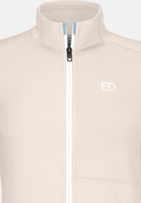 Beige zip-up jacket with high collar, white zipper, and small white logo on the left chest.