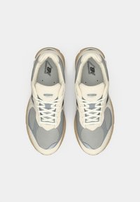 Pair of gray and beige New Balance running shoes with white laces, viewed from above on a plain white background.