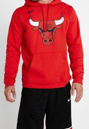 Sweat à capuche rouge avec un logo noir des Chicago Bulls, capuche avec cordon et poche kangourou. Porté avec un short de sport noir arborant un logo Nike blanc.