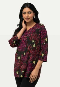 Tunic nera con un vivace motivo floreale viola e arancione, scollatura a V, maniche tre quarti e una vestibilità rilassata. Tessuto dalla superficie liscia.