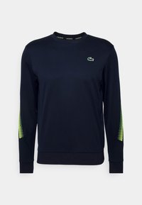 Navy long-sleeve sweatshirt made of textured material, featuring a green and yellow mesh pattern on the sleeves and a small logo on the chest.