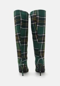 Bottes genoux vertes à carreaux en tissu texturé, dotées d'un bout pointu et de talons aiguilles noirs. Détail de fermeture éclair à l'arrière.