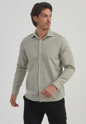 Chemise boutonnée à rayures en vert olive et blanc, avec un col, des manches longues et une poche poitrine, fabriquée dans un tissu lisse.