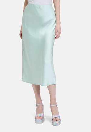 Jupe midi en satin vert menthe avec une texture lisse, présentant une silhouette droite et un éclat subtil. Assortie à des sandales à plateforme iridescentes.