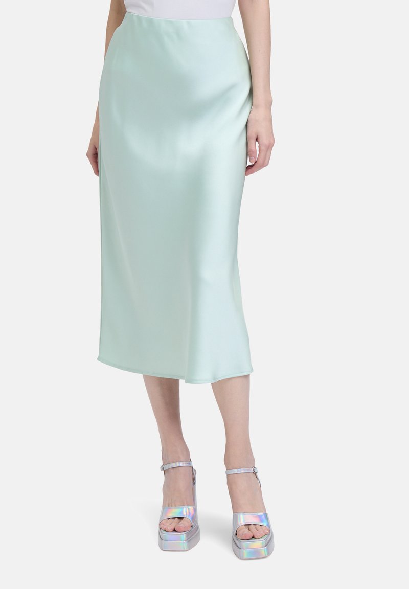 Jupe midi en satin vert menthe avec une texture lisse, présentant une silhouette droite et un éclat subtil. Assortie à des sandales à plateforme iridescentes.