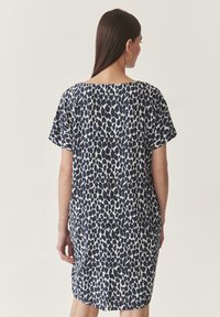 Kratka haljina s kratkim rukavima koja ima plavi i bijeli uzorak leopard printa, opušteni kroj i ravni rub s malim prorezom na leđima.