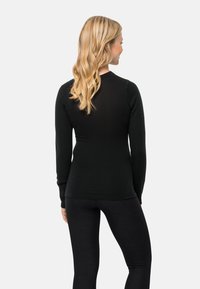 Schwarzes langärmliges Oberteil aus weichem Material, mit figurbetontem Design und Rundhalsausschnitt. Kombiniert mit schwarzen Leggings.