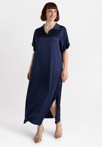 Navy blue maxi dress with a collar and short rolled sleeves, featuring a side slit for movement. Smooth texture with a sleek design.