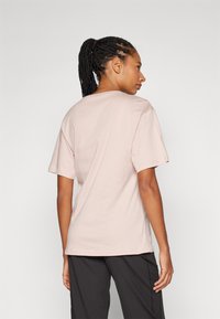 Lyser�ød T-shirt med korte ærmer lavet af bomuld, med en afslappet pasform og rund udskæring, synlige sømme på kanten og ærmerne.