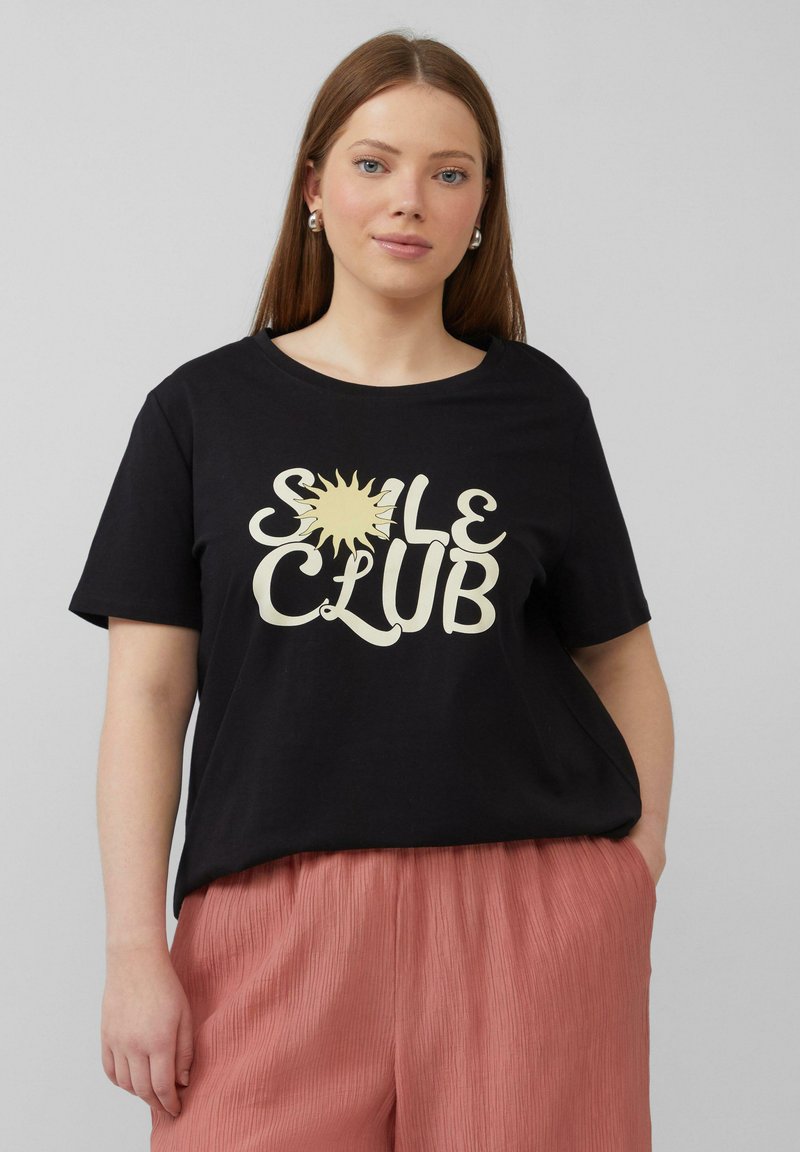 Zwarte t-shirt met een grote crèmekleurige zonafbeelding en de tekst "SOLE CLUB." Het shirt heeft een relaxte pasvorm en een ronde halslijn.