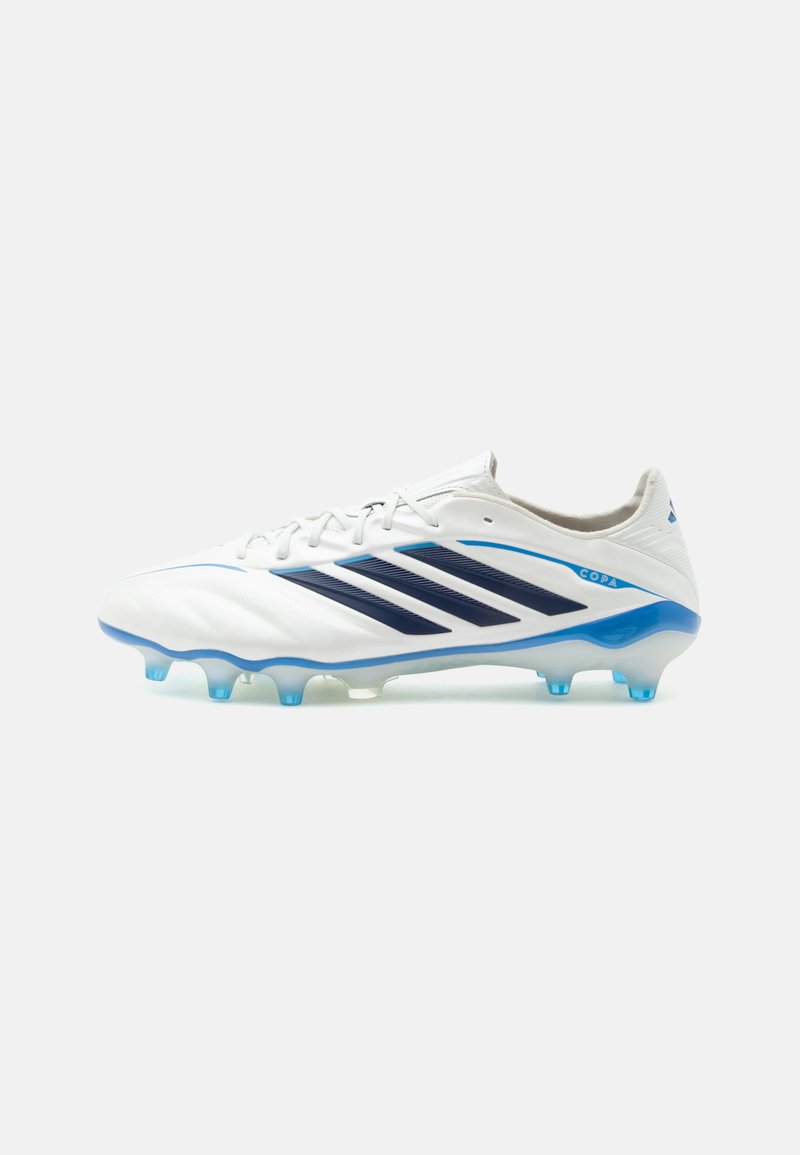Λευκό και μπλε ποδοσφαιρικό παπούτσι Adidas Copa με σκούρες μπλε ρίγες και μπλε τάπες, σχεδιασμένο για σκληρές επιφάνειες.