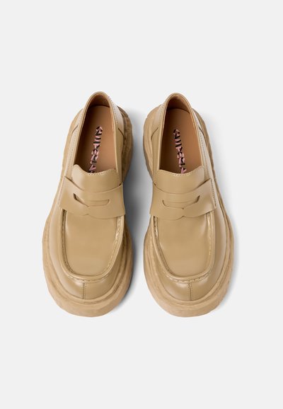 Beige leren instappers met een dikke rubberen zool, voorzien van een strikdetail en een ronde neus. Glad textuur en minimalistisch ontwerp.