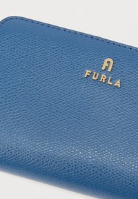 Blåt læderpung med en tekstureret overflade, der har et guldlogo "FURLA" prægede på forsiden. Rektangulær form med afrundede hjørner.