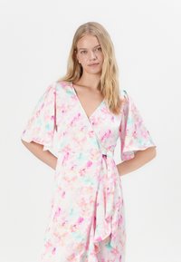 Φλοράλ φόρεμα με τύπωμα σε παστέλ ροζ και μωβ αποχρώσεις, κοντά φτερωτά μανίκια, V-λαιμόκοψη και ζώνη στον πλαινό μέρος. Ελαφρύ ύφασμα.