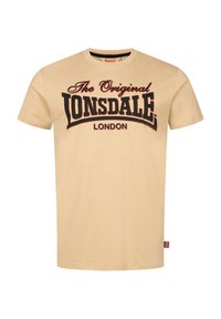 Beige kokvilnas T-krekls ar melniem treknraksta burtiem, kas nolasāmi "The Original Lonsdale London" ar sarkaniem akcentiem. Īsas piedurknes, apaļa kakla izgriezums.