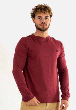 T-shirt a maniche lunghe color maroon realizzato in tessuto morbido, con collo rotondo e un piccolo logo di un albero sulla parte sinistra del petto.