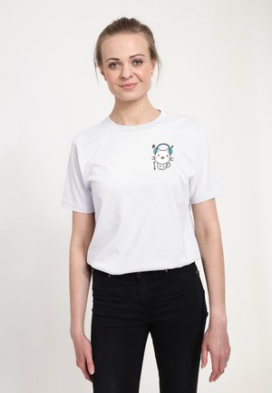 White cotton t-shirt featuring a printed illustration of a cartoon cat with headphones on the left chest area. Black jeans are worn.