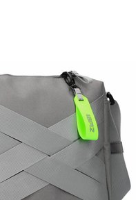 Grau gestreifte Stofftasche mit diagonalen Trägerdetails, einem kontrastierenden grünen Reißverschluss-Zipper und einem schwarzen Reißverschluss, mit glatter Textur und robustem Design.