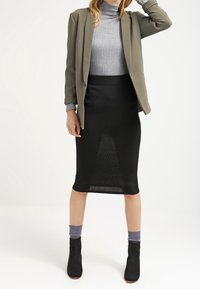 Olive green blazer over a grey turtleneck, paired with a black pencil skirt. Black ankle boots and grey socks complete the outfit.