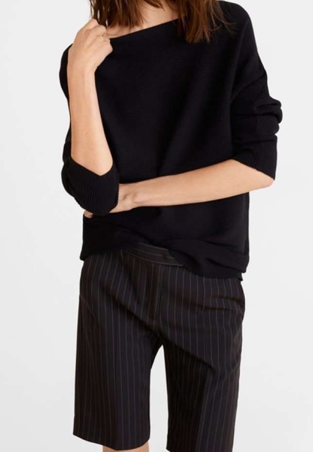 Pull noir texturé avec un large col, associé à un short foncé longueur genou orné de rayures blanches verticales. Coupe décontractée et confortable.