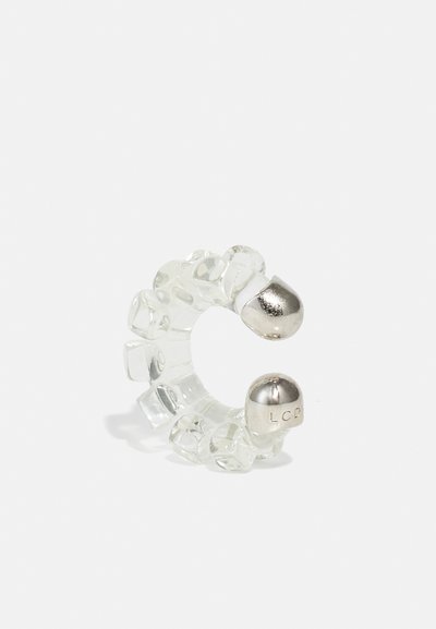 Bague flexible transparente avec des cubes en résine claire et des extrémités argentées métalliques avec du texte en relief, formée en un design circulaire.