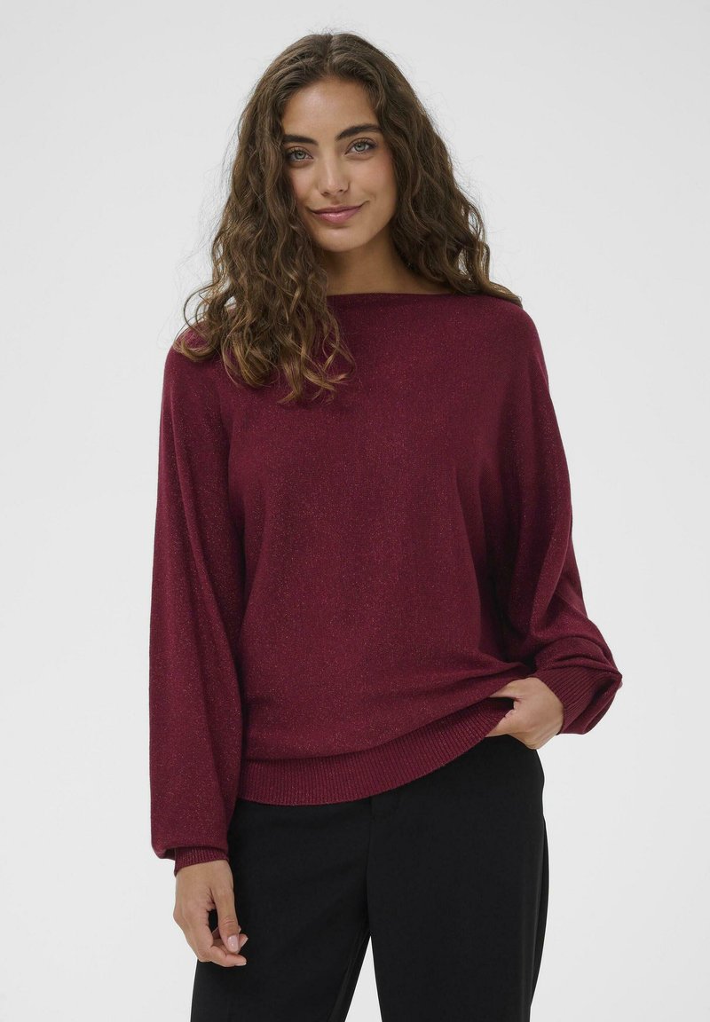 Pulover tricotat burgundy cu decolteu tip bateau, mâneci lungi și tiv ribflat. Textură moale cu un ușor luciu pe întreaga suprafață. Asortat cu pantaloni închiși la culoare.