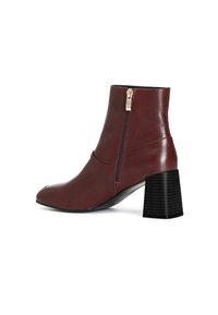 Stivale alla caviglia in pelle marrone con punta quadrata, cerniera laterale e tacco spesso nero con texture rigata.