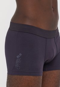 Marineblaue Boxershorts aus weichem Stoff, mit einem breiten elastischen Bund und einem kleinen aufgedruckten Logo auf der linken Seite.