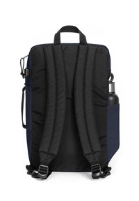 Mochila marina con correas acolchadas negras, asa superior y bolsillo lateral para una botella de agua. Tejido texturizado y hebillas de correa ajustables.