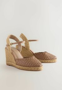 Woven brown espadrille wedge sandals with a peep-toe design, ankle strap, and textured jute platform. Smooth interior lining and supportive heel.