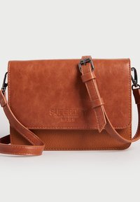Borsa a tracolla in finta pelle marrone con superficie testurizzata, flap magnetico, tracolla regolabile e dettaglio di branding in rilievo sul fronte.