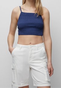 Marineblå crop top med struktureret stof og tynde stropper, parret med hvide cargo shorts med sidelommer og en afslappet pasform.