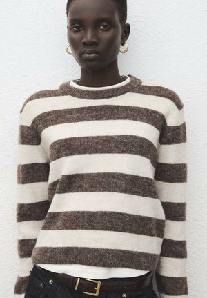 Maglione a righe marrone e crema con scollo rotondo e maniche lunghe, indossato sopra una camicia bianca, abbinato a una cintura scura.