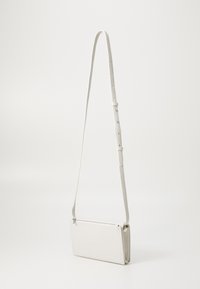 Bolso cruzado de cuero blanco con un acabado texturizado, forma rectangular y una larga correa ajustable. Presenta un cierre con cremallera y detalles sutiles.