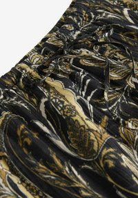 Tissu noir avec un motif floral en or et blanc, à la texture froncée et doté d'une ceinture élastique. Convient pour des vêtements féminins.