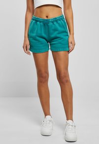 Teal cotton shorts with an elastic waistband, side pockets, and a relaxed fit. Features a smooth texture and stitched hems.