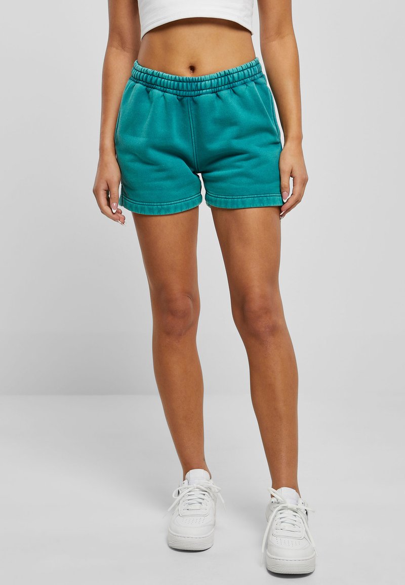 Teal cotton shorts with an elastic waistband, side pockets, and a relaxed fit. Features a smooth texture and stitched hems.