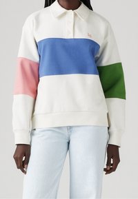 Pullover color-block in cotone misto bianco, blu, rosa e verde. Presenta un colletto e un'apertura con tre bottoni. Texture morbida.