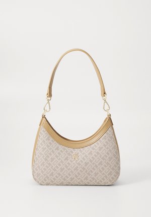 Beige håndtaske med en buet øverste kant, lysebrun læderkant, mønstret stof, kort skulderrem og lille gyldent logo foran.
