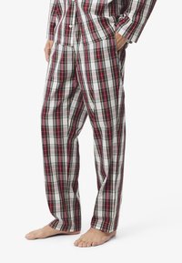 Kockás pizsamanadrág fehér, piros és zöld árnyalatokban; könnyű anyag; laza fazon; oldalsó zsebek; lapos derékpánt; bokáig érő.