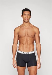 Svarte boxerbriefs med en hvit midjebånd som har Levi's-logoen. Stoffet ser glatt ut med en tettsittende passform.