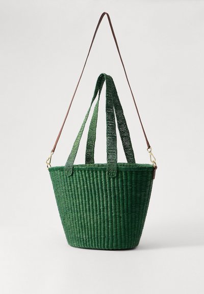 Borsa tote verde intrecciata con forma rotonda, dotata di doppie maniglie intrecciate e una tracolla in pelle marrone, che presenta una superficie texturizzata.