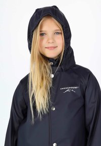 Giacca impermeabile blu navy con cappuccio foderato, bottoni a pressione e logo "SWEDEMOUNT". Texture liscia con design aderente.