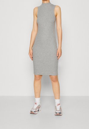 Robe moulante grise sans manches jusqu'aux genoux, associée à des chaussettes blanches et des baskets de sport blanches et roses, portée par une personne debout.